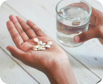 Comprimés dans la main avec un verre d’eau | NY Center